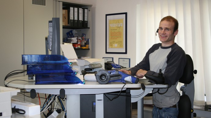 Mann mit Behinderung am Schreibtisch
