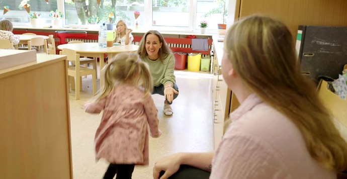 Bild: Ein kleines Mädchen läuft einer Frau mit einem grünen Pullover in die Arme.